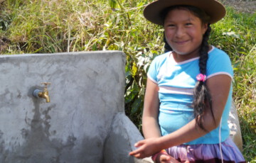 Ein Mädchen aus Peru steht an einer Wasserstelle